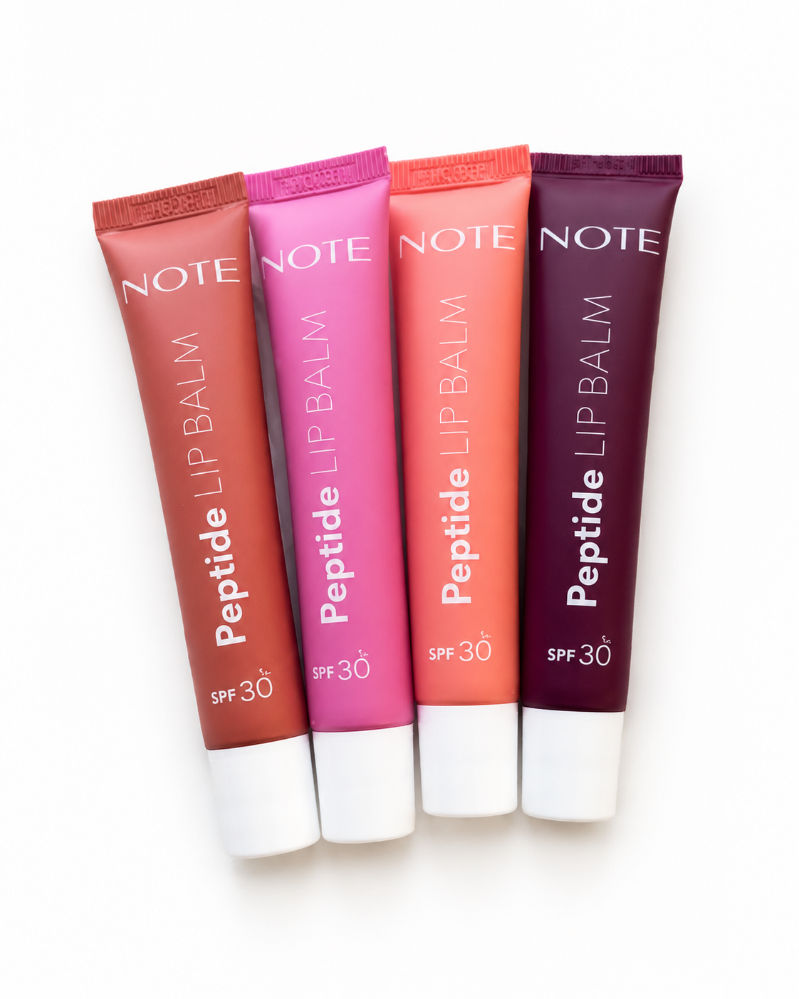 Peptide lip balm SPF 30 by NOTE in four tinted shades, matte finish, white caps, flat lay view