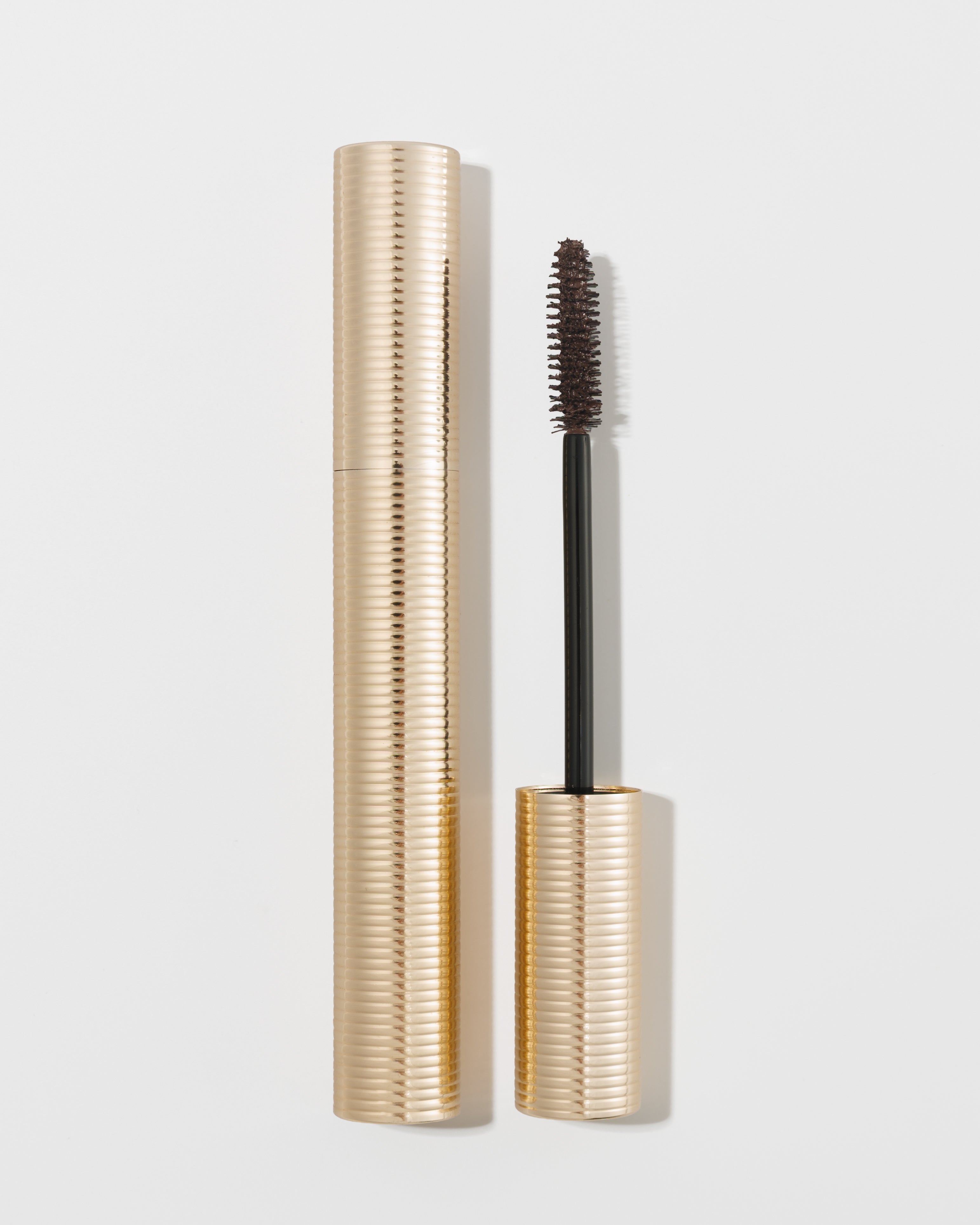 Gold ribbed mascara tube with black wand and spiral brush by KASH Beauty, shown open on white background