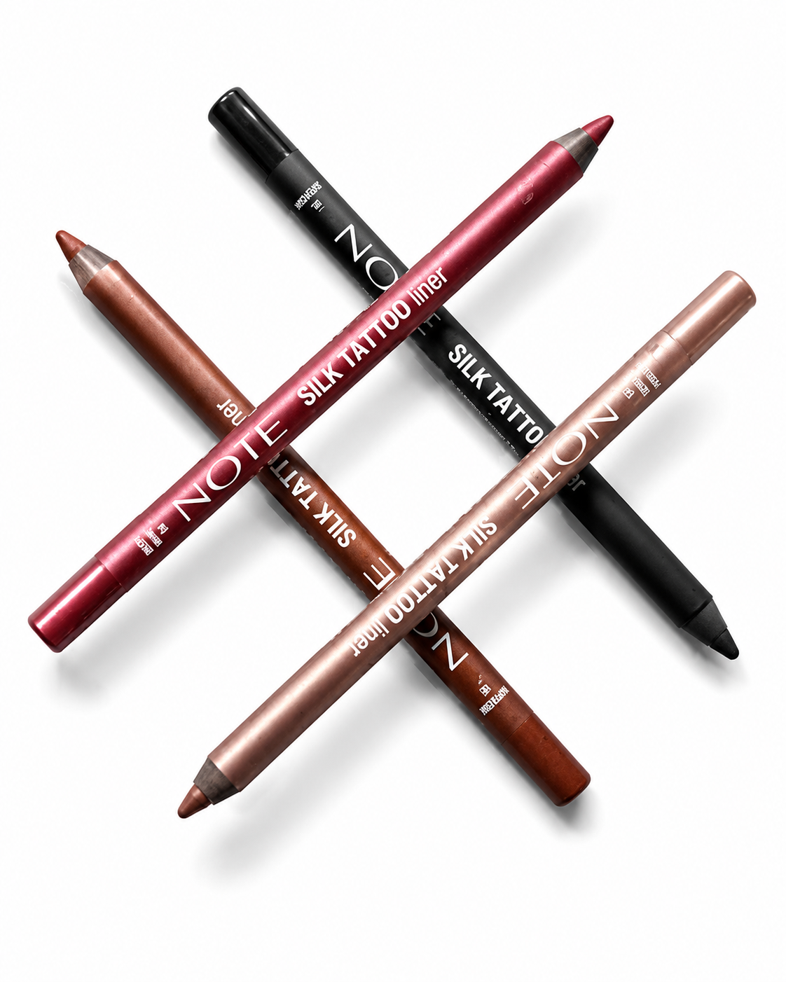 Four lip liner pencils from NOTE SILK TATTOO LINER arranged in a crossed pattern on a white background. The shades include a deep berry red, a warm bronze-brown, a metallic copper-rose, and a classic black.