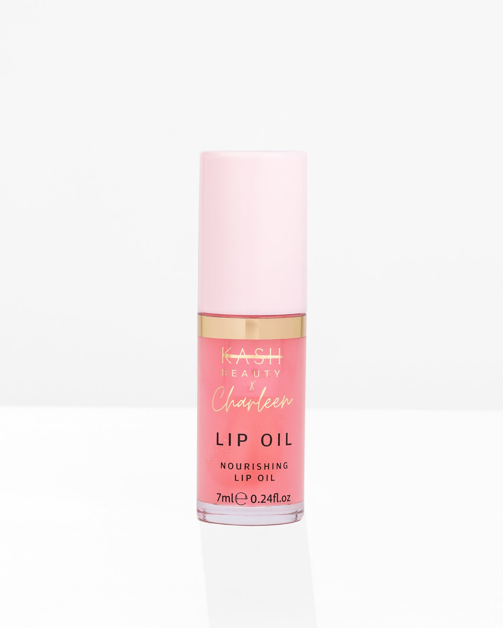 Pink glass lip oil bottle with gold band and cap by KASH Beauty, featuring clear label with black and gold text, front view on white background