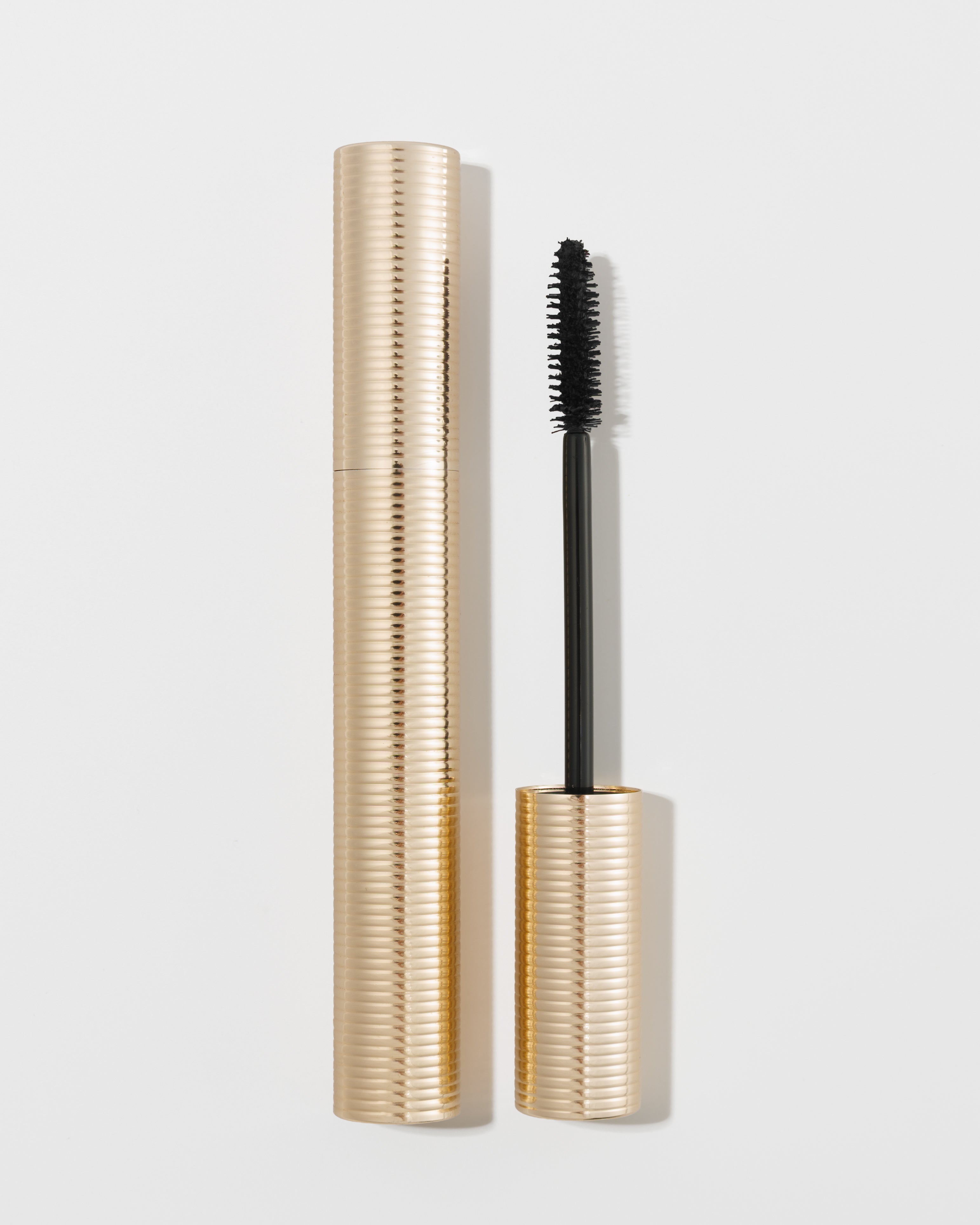 Gold ribbed mascara tube with black wand by KASH Beauty, open and displayed upright on white background