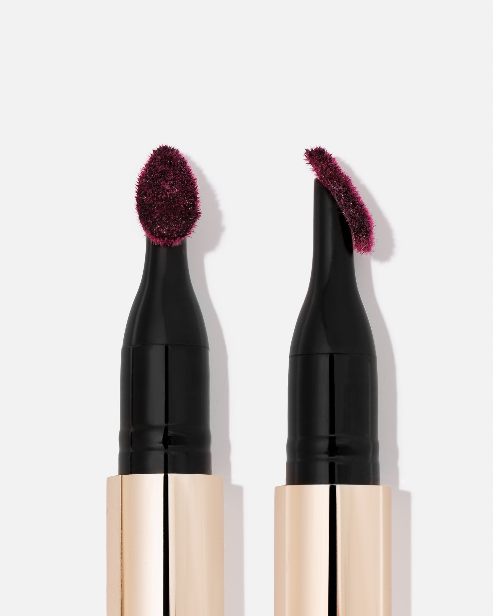 Deep plum lip stain by KASH Beauty with black applicator and gold-toned barrel, shown from top view with textured brush tips. GIVE US BEAUTY NEWRY