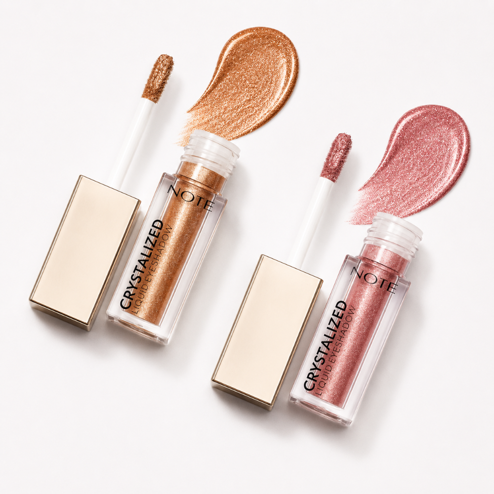 Two shimmer liquid lip glosses from NOTE Crystallized eyeshadow in metallic rose gold and champagne gold shades, shown with their caps off and swatches of the gloss above the tubes on a white background.