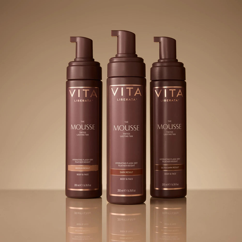 Three bottles of Vita Liberata The Mousse on a reflective surface with a beige background